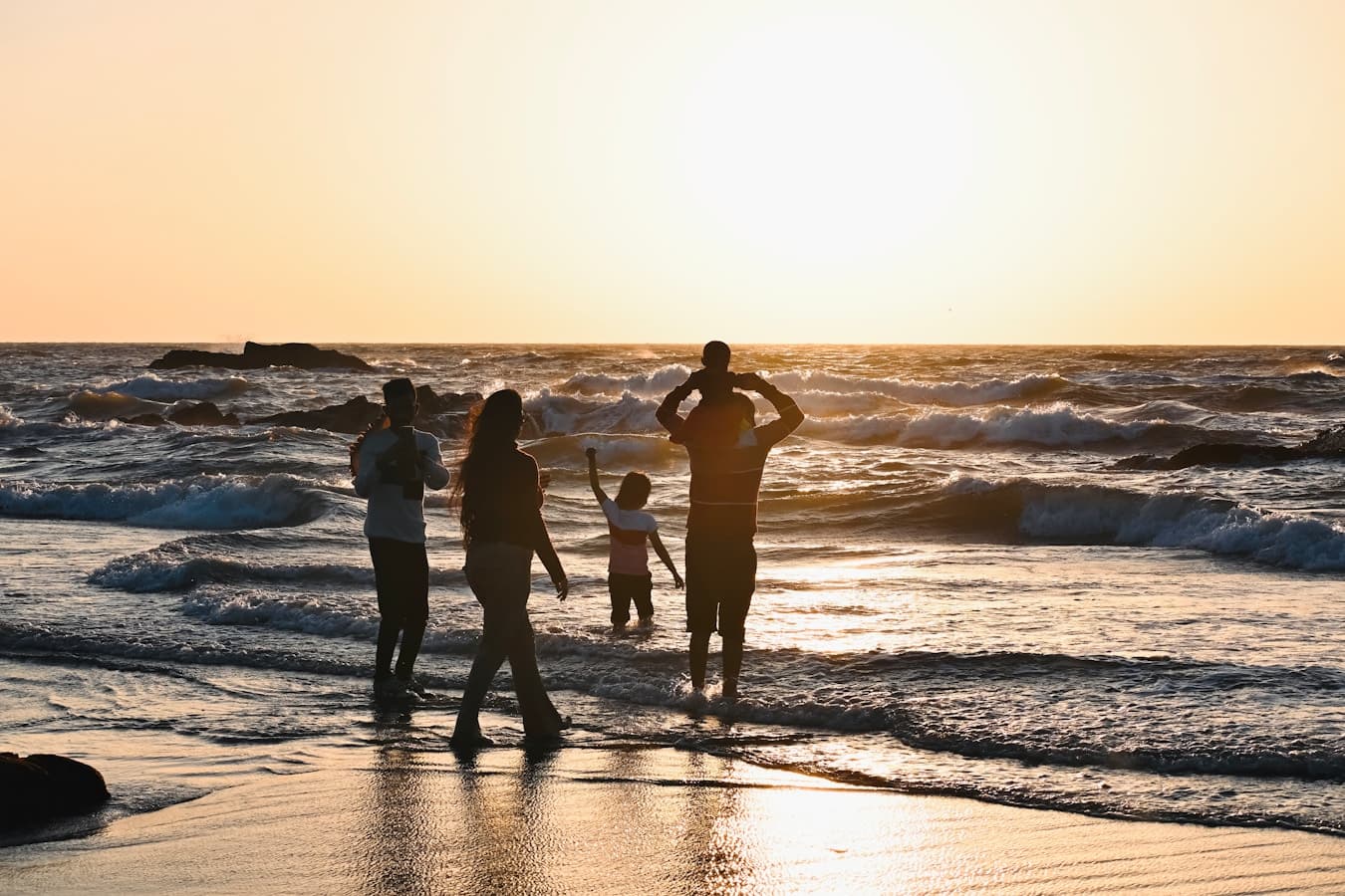 A family with three kids playing in the waves at sunset on a Costa Rica beach